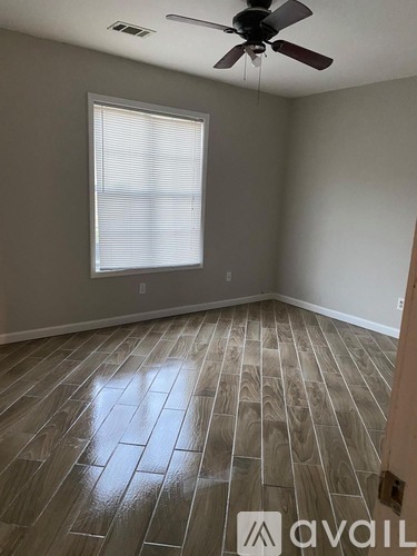 A room with wooden flooring and a ceiling fan.