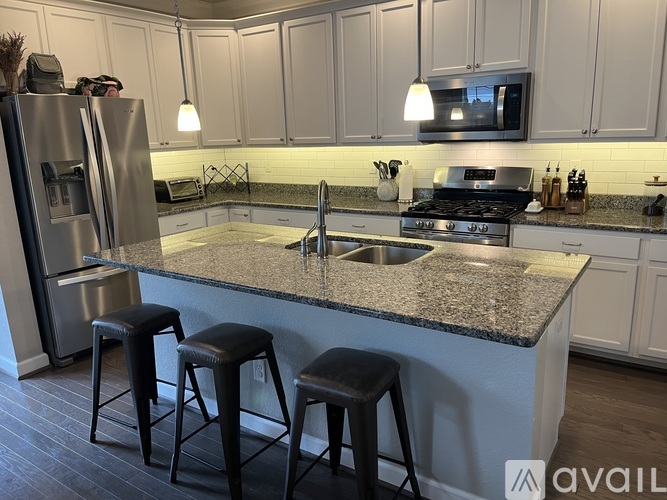 A kitchen with granite countertops and a stainless steel refrigerator.