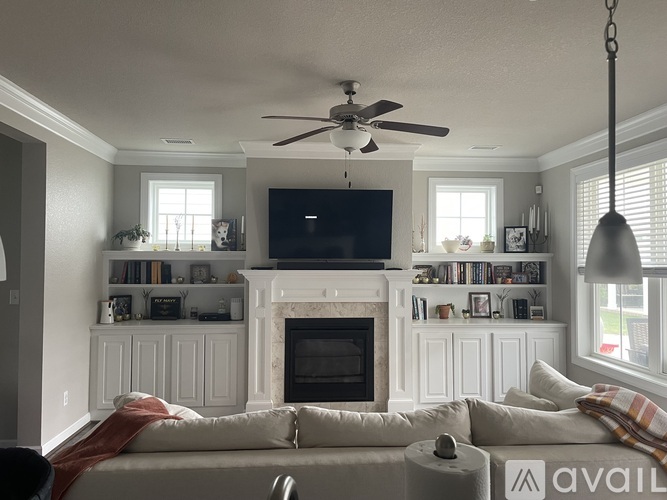 A living room with a fireplace and a television mounted above it.