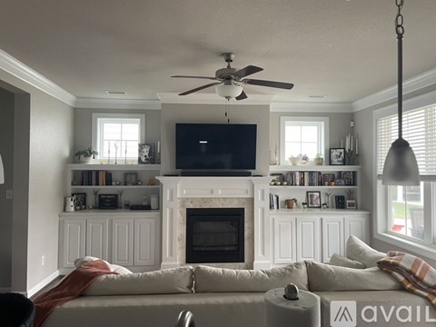 A living room with a fireplace and a television mounted above it.