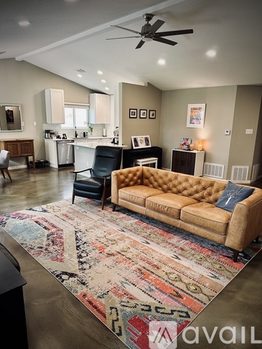 A living room with a brown couch and a rug with the word "avail" on it.