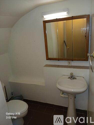 A bathroom with a toilet, sink and mirror.