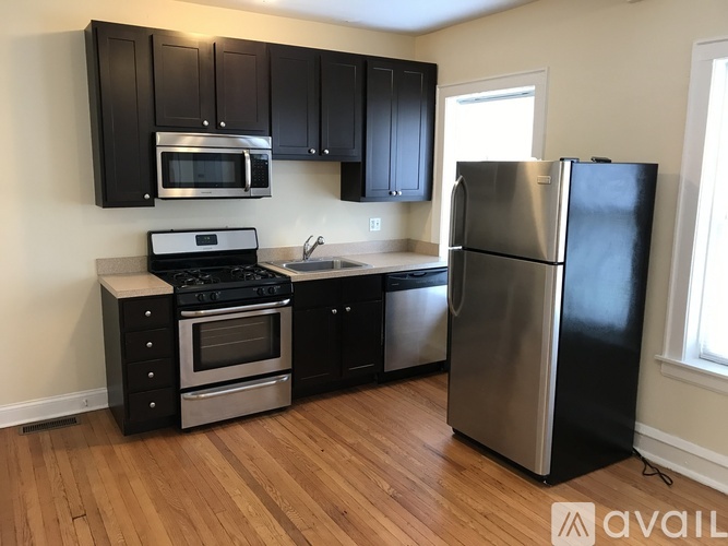 A kitchen with black cabinets and a stainless steel refrigerator.