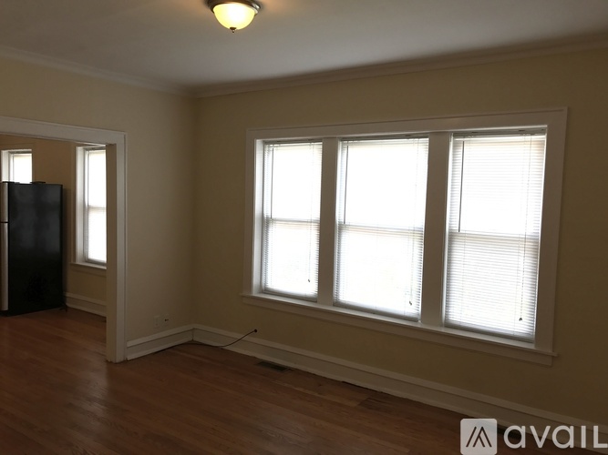 A room with a black fridge and wooden floors.