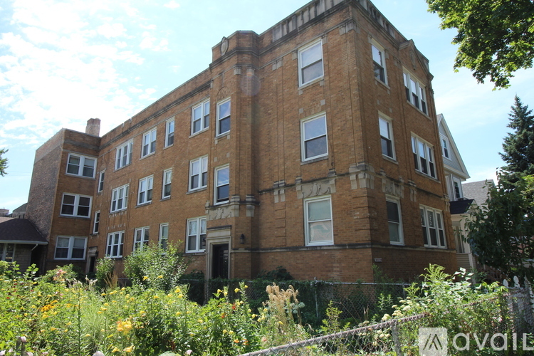 A large, old brick building with many windows and a fence in front.