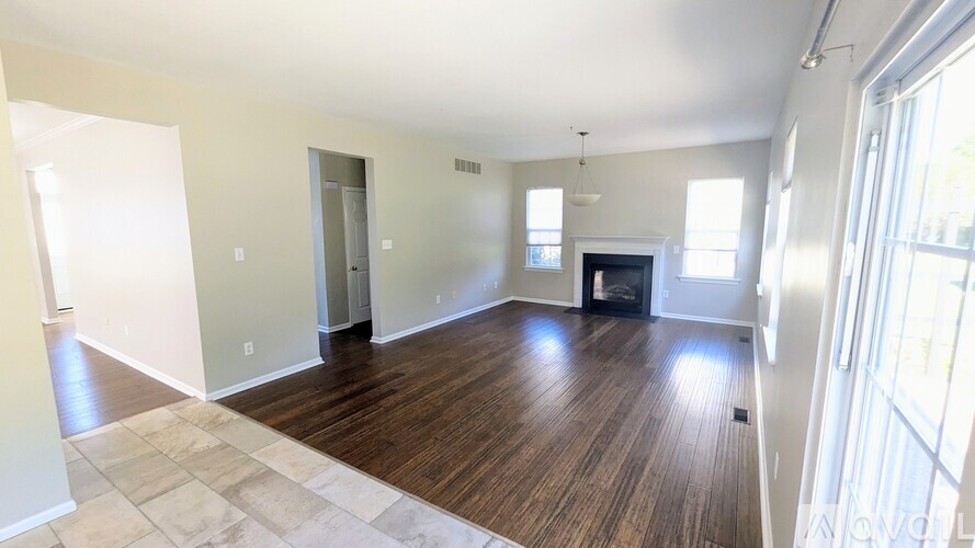 A spacious living room with wood flooring and a fireplace.