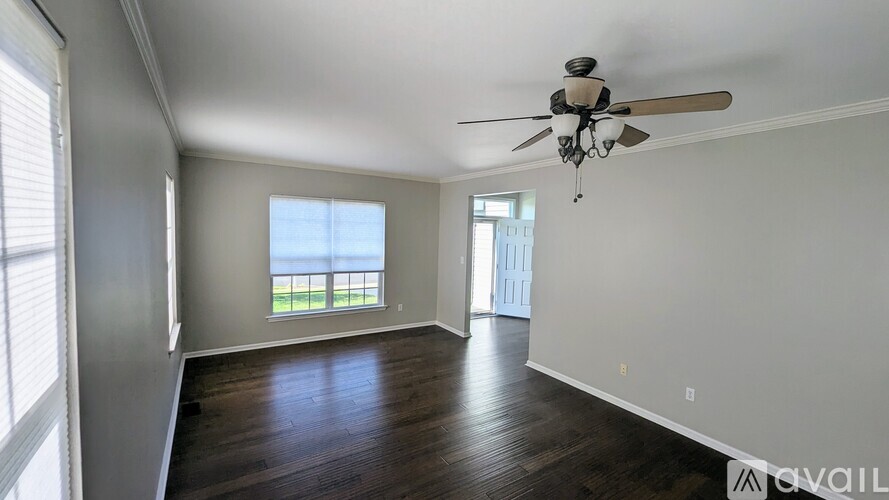 A spacious room with a ceiling fan and wooden flooring.