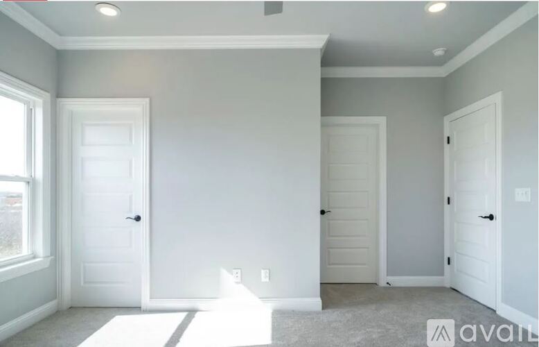 A room with white doors and a window with sunlight shining through.