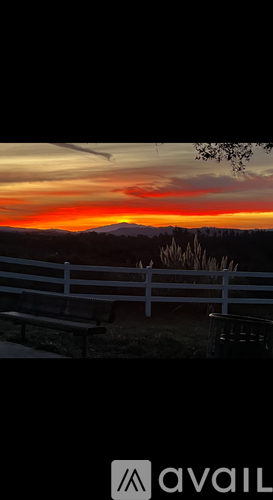 A sunset view with a white fence and a bench.