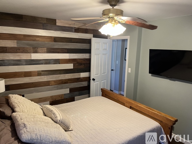 A bedroom with a bed, a ceiling fan, and a wooden wall.