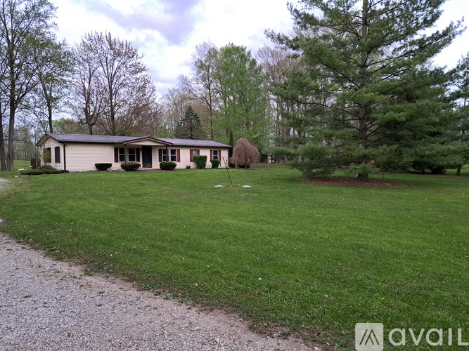 A house with a green lawn and trees in the background.