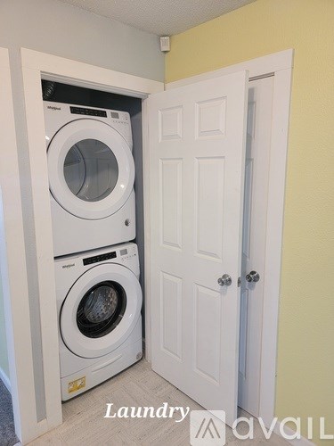 A white door is open to reveal a white washer and dryer in a small laundry room.