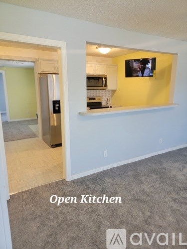 A kitchen with an open refrigerator and a microwave on the counter.