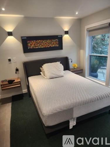 A bedroom with a large bed and a painting above it.