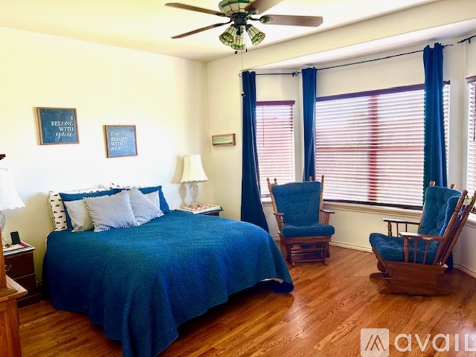 A bedroom with a bed, chair, and ceiling fan.