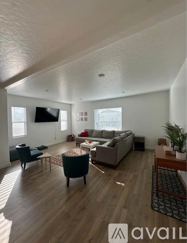 A living room with a couch, chairs, and a television.