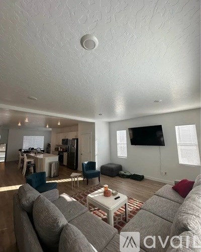 A living room with a grey couch and a television on the wall.