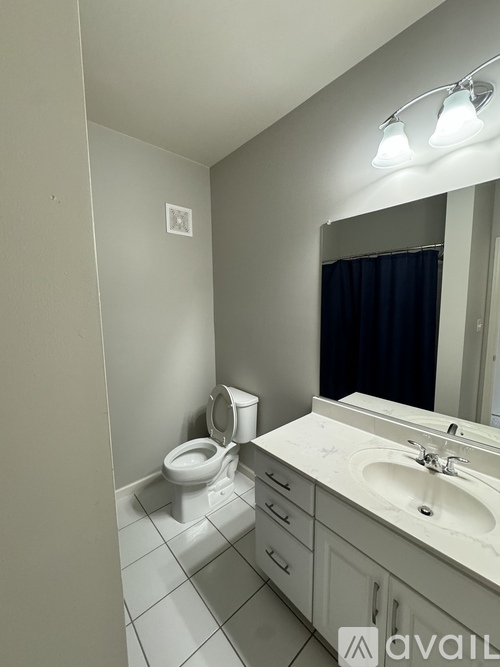 A bathroom with a toilet, sink, and mirror.