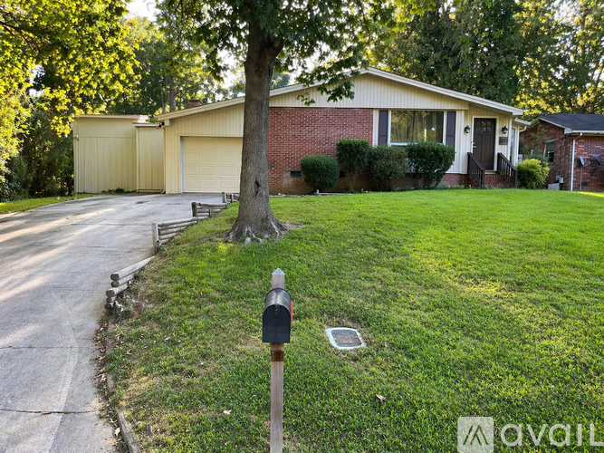 A house with a garage and a tree in front of it.