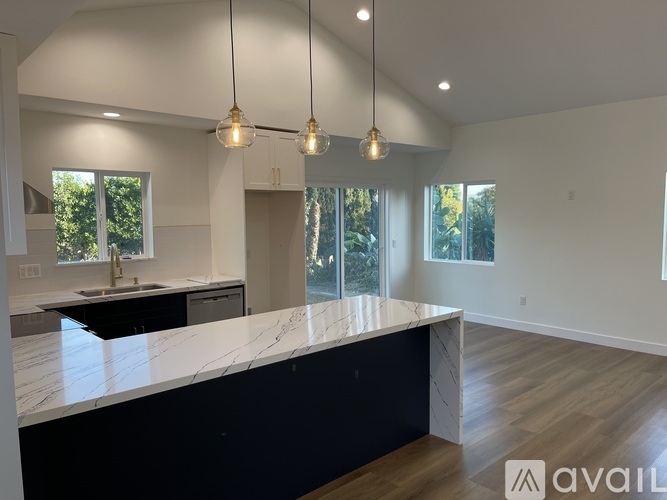 A modern kitchen with a marble countertop and pendant lights.