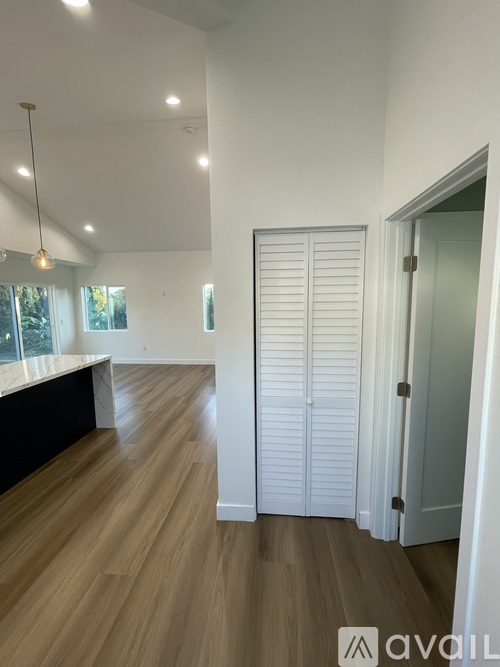 A room with white walls and wooden flooring with a white door.
