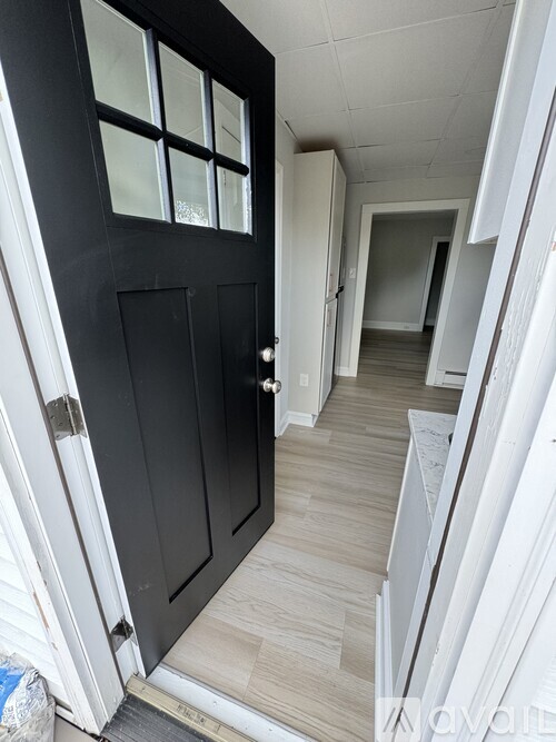 A black door with a glass window is open.