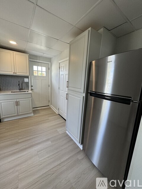 A kitchen with a stainless steel refrigerator and wooden flooring.