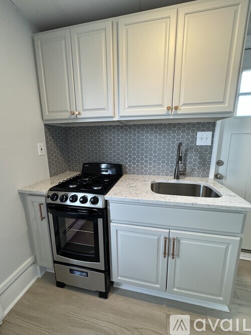 A kitchen with a stove, sink, and cabinets.