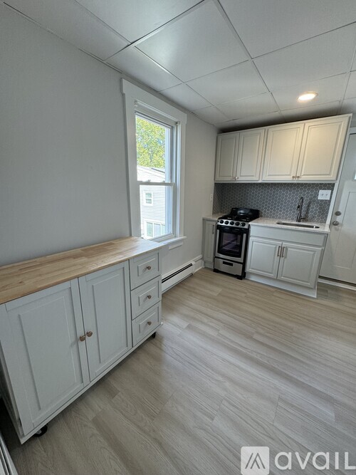 A kitchen with white cabinets and a wooden countertop.