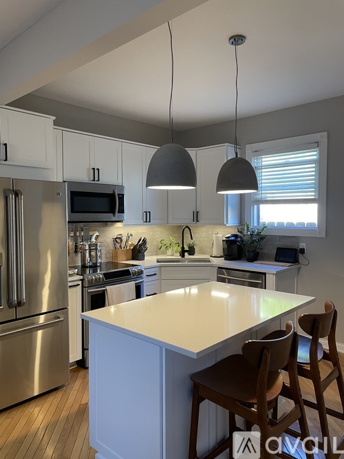 A kitchen with a white island and wooden chairs.