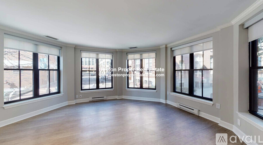 A spacious room with wooden floors and large windows.
