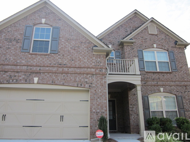 A brick house with a garage door and a sign that says "available".