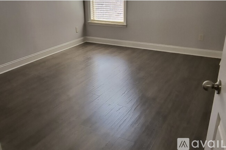 A room with wooden flooring and a door on the right side.