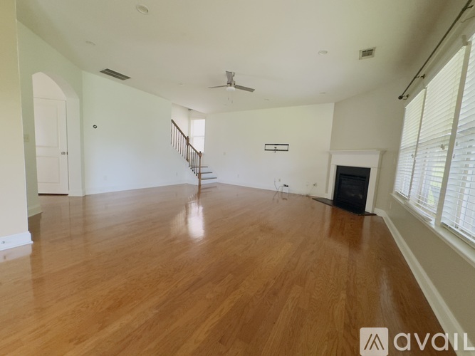 A spacious room with wooden floors and a staircase.