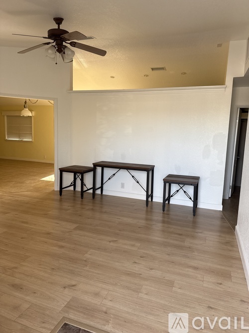 A room with a ceiling fan and three stools.