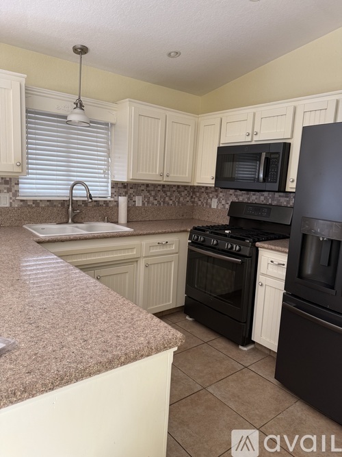 A kitchen with granite countertops and black appliances.