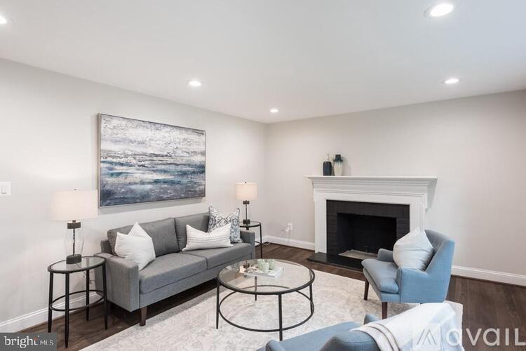 A living room with a grey couch, a fireplace, and a painting on the wall.