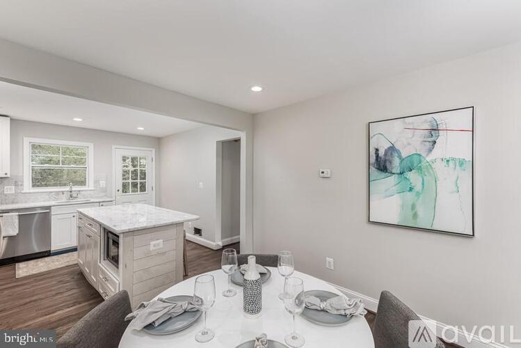 A modern dining room with a table set for two and a painting on the wall.