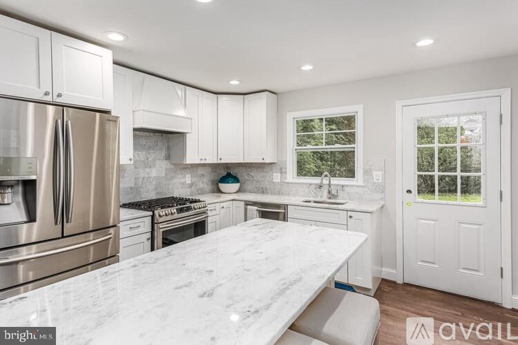 A kitchen with white cabinets and a marble countertop.
