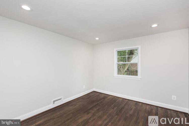 A room with wooden floors and a window showing trees outside.