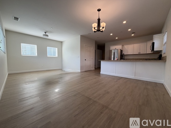 A spacious room with wooden flooring and a chandelier hanging from the ceiling.