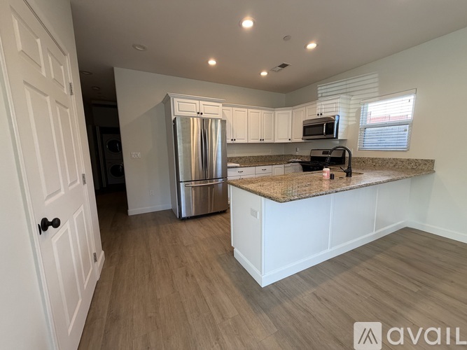 A kitchen with white cabinets and a stainless steel refrigerator.