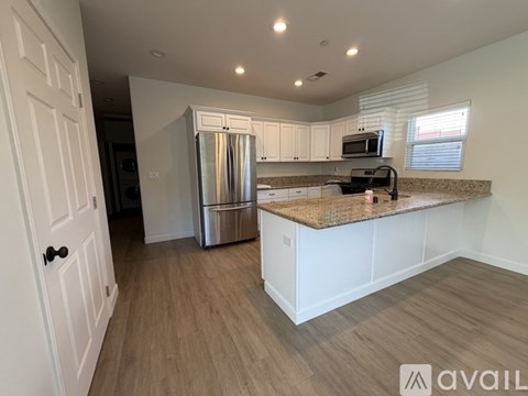 A kitchen with white cabinets and a stainless steel refrigerator.