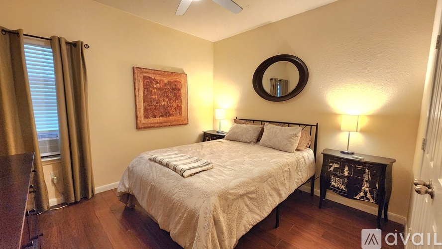 A bedroom with a bed, a lamp, and a painting on the wall.