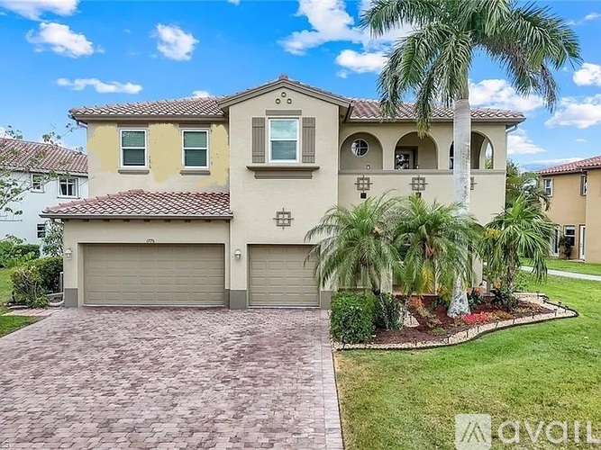 A house with a driveway and palm trees in front.