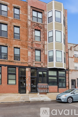 A building with a mix of brick and modern design with a car parked in front.