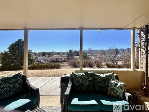 A balcony with two chairs and a table is overlooking a residential area.