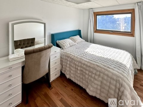 A bedroom with a bed, dresser, and mirror.