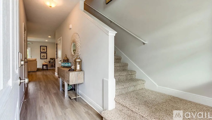 A hallway with a staircase and a table with a mirror on it.