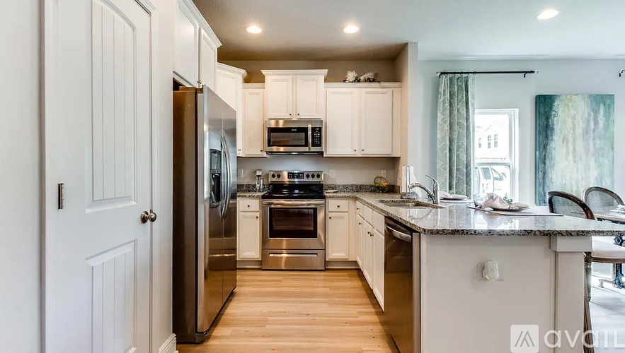 A modern kitchen with white cabinets and stainless steel appliances.
